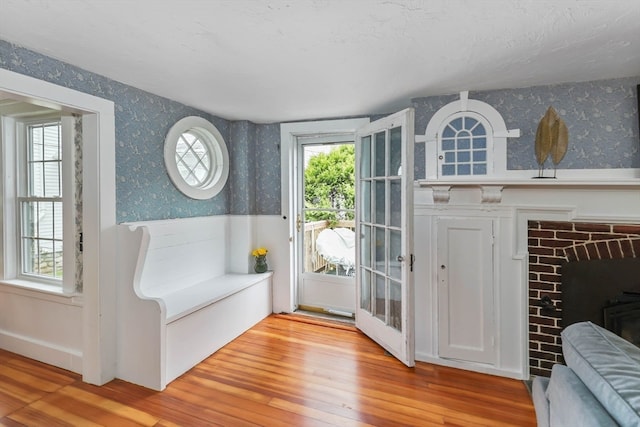 interior space featuring a wealth of natural light, light wood-type flooring, and a brick fireplace