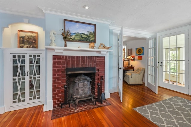 living room featuring a textured ceiling, ornamental molding, a fireplace, and wood-type flooring