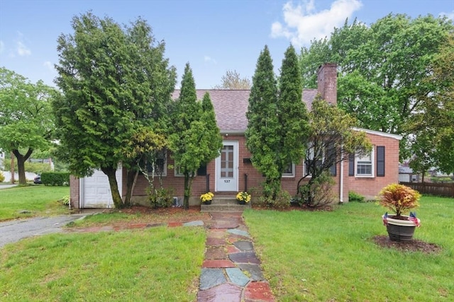 view of property hidden behind natural elements featuring driveway, brick siding, a chimney, roof with shingles, and entry steps