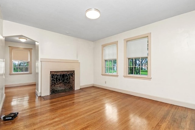 unfurnished living room with healthy amount of natural light, wood finished floors, and baseboards