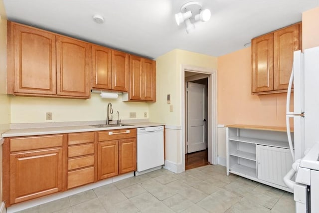 kitchen featuring a sink, white appliances, light countertops, and light tile patterned floors