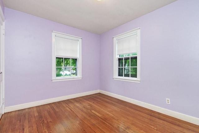 unfurnished room featuring plenty of natural light, baseboards, and wood finished floors