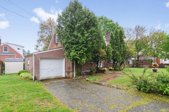 view of front of home featuring a front yard, brick siding, and asphalt driveway