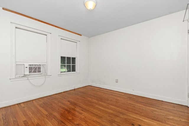 unfurnished room featuring wood finished floors, baseboards, and cooling unit