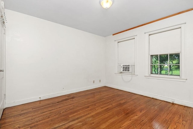 empty room featuring hardwood / wood-style floors, baseboards, and cooling unit