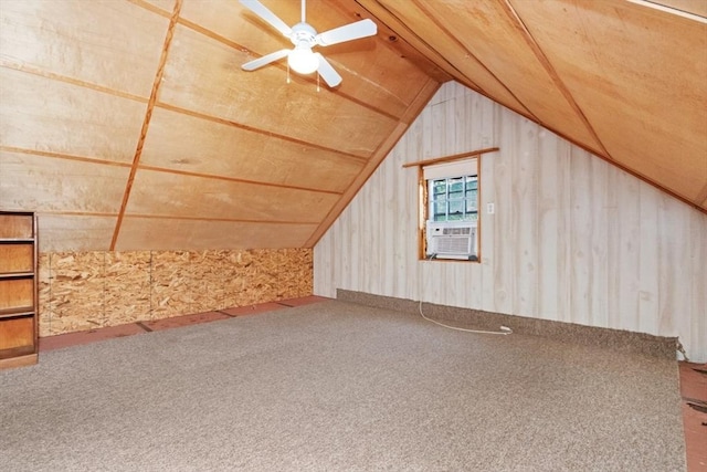 additional living space with lofted ceiling, cooling unit, wooden walls, a ceiling fan, and carpet