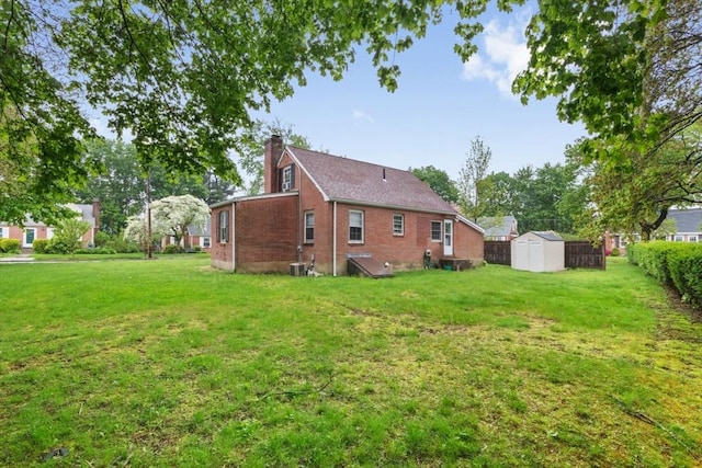 back of house featuring a storage shed, a chimney, brick siding, an outdoor structure, and cooling unit