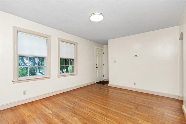 spare room with light wood-type flooring and baseboards