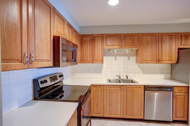 kitchen with brown cabinets, a sink, stainless steel appliances, light countertops, and backsplash