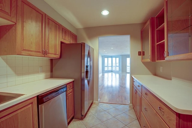 kitchen featuring light tile patterned floors, backsplash, dishwasher, and light countertops