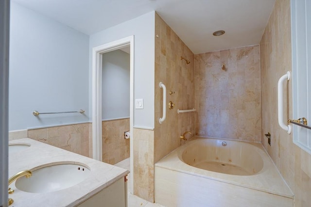 full bathroom with a combined bath / shower with jetted tub, wainscoting, tile walls, and vanity