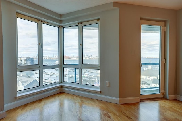 unfurnished room featuring light wood finished floors, a view of city, and baseboards