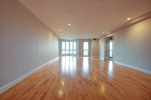 empty room with recessed lighting, light wood-style flooring, and baseboards