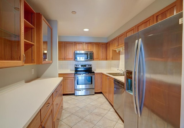 kitchen featuring light tile patterned floors, a sink, light countertops, appliances with stainless steel finishes, and backsplash