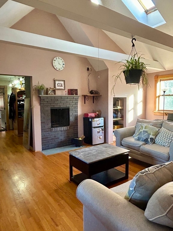 living room featuring hardwood / wood-style floors, lofted ceiling with skylight, and a fireplace