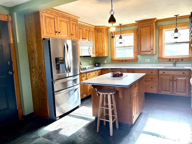 kitchen with pendant lighting, a center island, white appliances, a kitchen breakfast bar, and sink