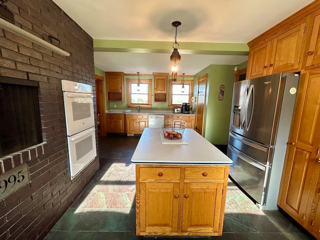 kitchen featuring a center island, sink, hanging light fixtures, brick wall, and white appliances