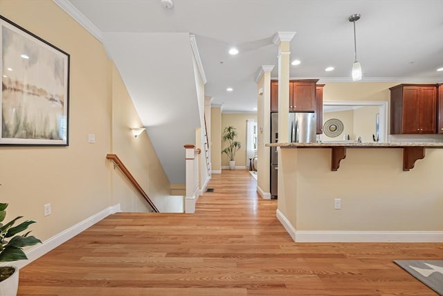 960 Main St Unit C, Woburn, MA 01801 - kitchen with a breakfast bar, freestanding refrigerator, crown molding, hanging light fixtures, and light wood-type flooring