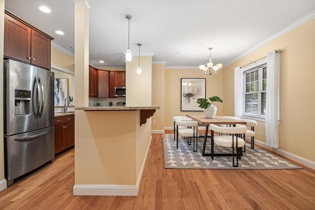 960 Main St Unit C, Woburn, MA 01801 - kitchen with appliances with stainless steel finishes, crown molding, baseboards, a kitchen bar, and light wood-style floors