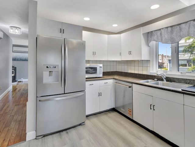 10 Vernon Ave, Hull, MA 02045 - kitchen featuring appliances with stainless steel finishes, light wood finished floors, dark countertops, decorative backsplash, and white cabinetry