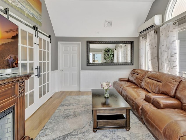 10 Vernon Ave, Hull, MA 02045 - living room featuring lofted ceiling, a wall unit AC, a barn door, wainscoting, and plenty of natural light