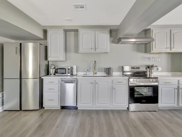 10 Vernon Ave, Hull, MA 02045 - kitchen with appliances with stainless steel finishes, white cabinetry, light countertops, and light wood-type flooring