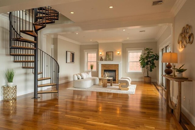 interior space featuring a glass covered fireplace, wood finished floors, visible vents, and baseboards