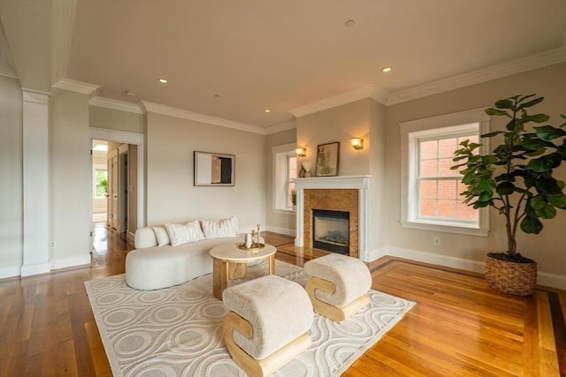 living room featuring baseboards, a high end fireplace, ornamental molding, wood finished floors, and recessed lighting