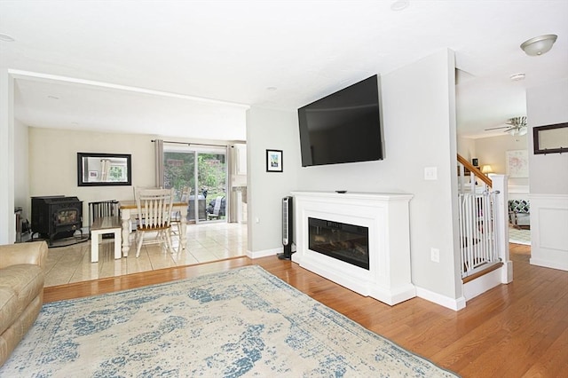 54 Clarke Rd, Sturbridge, MA 01518 - living area featuring wood finished floors, a wood stove, a ceiling fan, and a glass covered fireplace