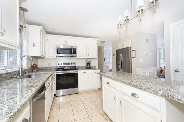 54 Clarke Rd, Sturbridge, MA 01518 - kitchen featuring stainless steel appliances, white cabinetry, a wainscoted wall, light tile patterned floors, and light stone counters
