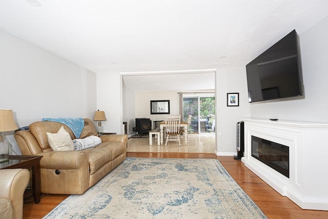 54 Clarke Rd, Sturbridge, MA 01518 - living area with wood finished floors, a glass covered fireplace, and a wood stove