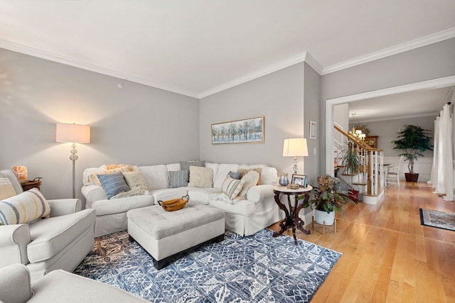 living room featuring light hardwood / wood-style floors, ornamental molding, and a notable chandelier