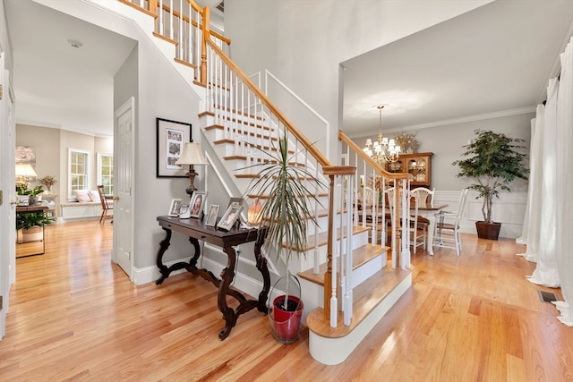 stairs featuring a chandelier, wood-type flooring, and ornamental molding