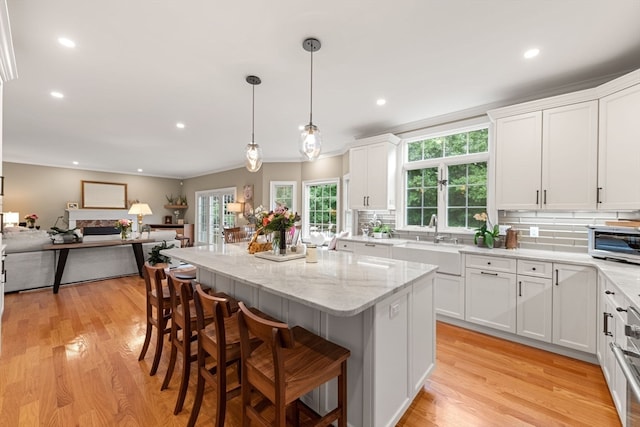 kitchen with white cabinets, tasteful backsplash, a kitchen island, and sink