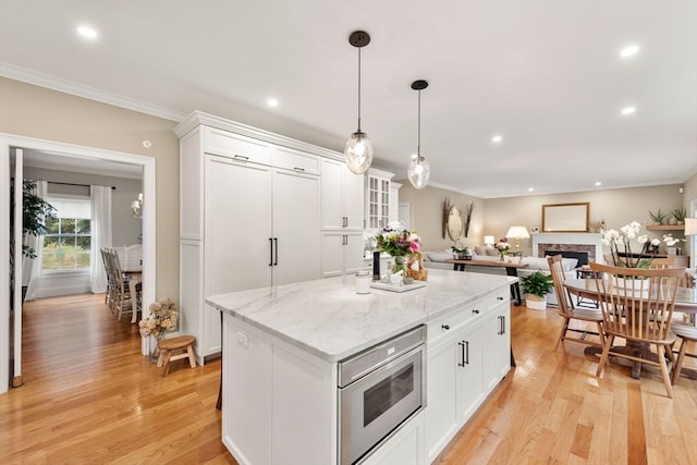 kitchen featuring white cabinets, a center island, ornamental molding, and light hardwood / wood-style flooring