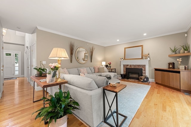 living room with a high end fireplace, light hardwood / wood-style floors, and crown molding