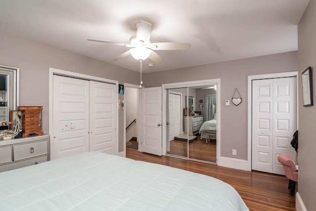 bedroom with ceiling fan, dark hardwood / wood-style floors, and two closets