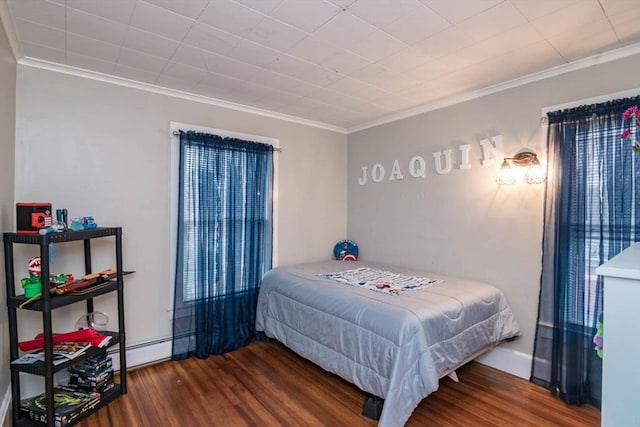 bedroom featuring dark hardwood / wood-style flooring, crown molding, and a baseboard heating unit