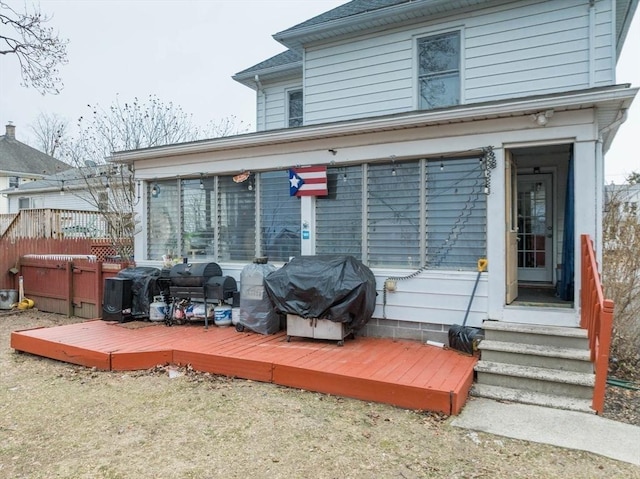 rear view of house featuring a jacuzzi and a wooden deck