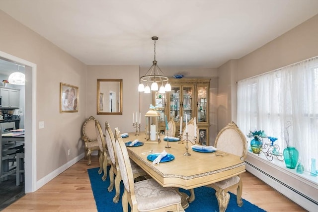 dining area with light hardwood / wood-style floors, an inviting chandelier, and a baseboard radiator