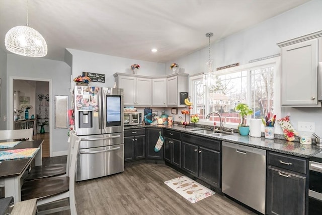 kitchen with appliances with stainless steel finishes, sink, pendant lighting, a notable chandelier, and white cabinets