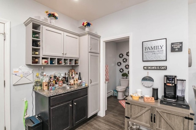 bar with light stone countertops, sink, a baseboard radiator, and dark hardwood / wood-style floors