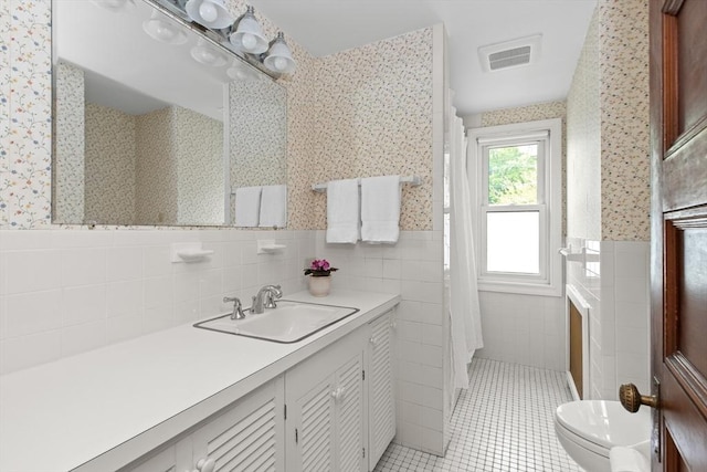 41 Clarke St, Lexington, MA 02421 - bathroom featuring wallpapered walls, wainscoting, tile walls, toilet, and tile patterned flooring