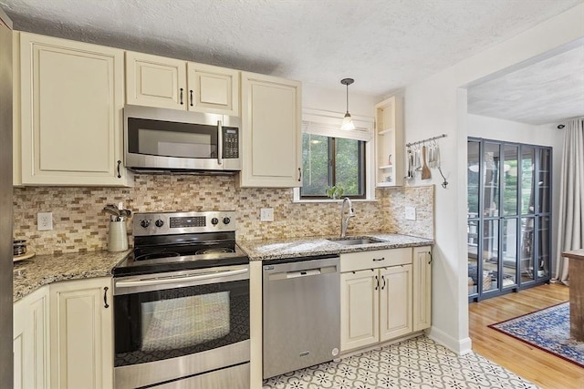 34 Staffordshire Ln Unit 34, Concord, MA 01742 - kitchen featuring stainless steel appliances, cream cabinetry, a sink, plenty of natural light, and a textured ceiling