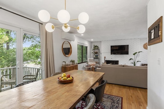34 Staffordshire Ln Unit 34, Concord, MA 01742 - dining space with a wall mounted AC, a brick fireplace, wood finished floors, and a chandelier