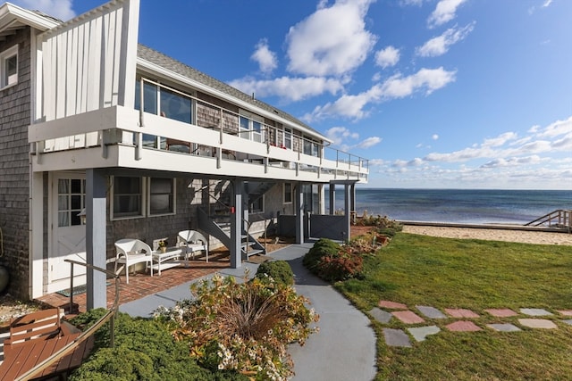 exterior space featuring a patio area, a water view, a beach view, and a balcony