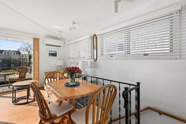 dining space with hardwood / wood-style floors, a wall mounted AC, and lofted ceiling