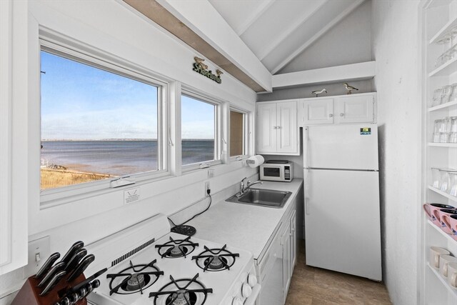 kitchen featuring sink, vaulted ceiling, white appliances, a water view, and white cabinets