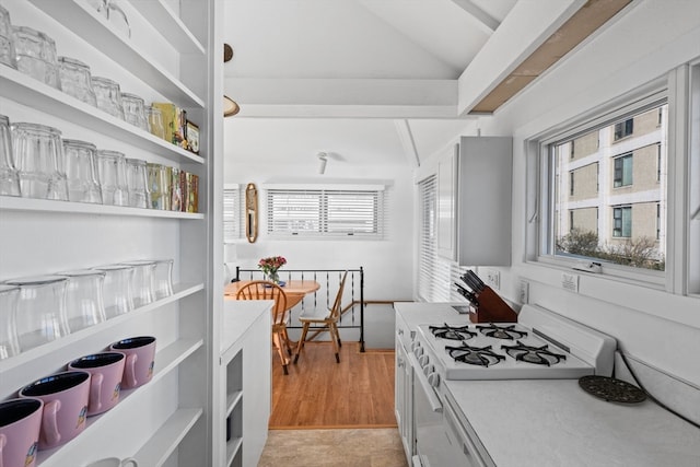 kitchen with light hardwood / wood-style floors, lofted ceiling, and white gas range oven