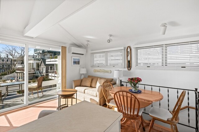 dining space with lofted ceiling with beams, a wall unit AC, and a wealth of natural light